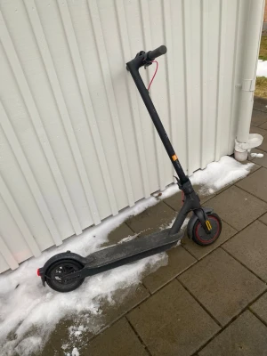 Svart elscooter med digital display - Elscooter i svart med röda detaljer och digital display på styret. Utrustad med ringklocka, handbroms och LED-belysning. Scootern har robusta däck och en stilren, minimalistisk design. Perfekt för smidig transport i stan. Elscootern är lite sliten men batteriet är som nytt knappt använd köptes till sommaren förra året 