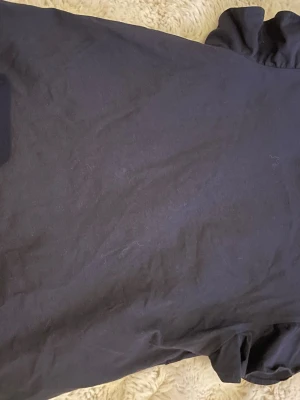 Mörkblå tröja från Gina Tricot - En enkel svart tröja från Gina Tricot i mjukt bomullsmaterial. Tröjan har en rak passform och kort längd, perfekt för en clean och stilren look. Passar dig som gillar minimalistiskt mode.