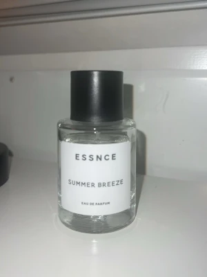 ESSNCE Summer Breeze Eau de Parfum - Fräsch parfym från ESSNCE med namnet Summer Breeze. Flaskan är rund och genomskinlig med svart lock och vit etikett. Modern och stilren design som passar perfekt i badrumshyllan. Doften är en Eau de Parfum och ger en somrig känsla. Den luktar så himla gott och på bilderna ser ni hur mycket som har använts och det är inte mycket☺️❣️Säljer då jag ska köpa en annan parfym☺️❣️Perfekt nu inför våren 