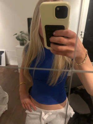 Blå croppad topp med öppen rygg - Snygg blå croppad topp med korta ärmar och öppen rygg. Tight passform som framhäver figuren och ger en modern look. Perfekt att styla med höga byxor eller kjol för en trendig outfit.