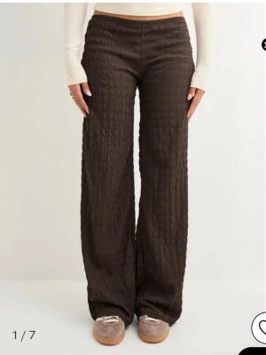 Bruna vida leggings med struktur - Säljer ett par bruna leggings med vid passform och snygg struktur i tyget. Det är från Nelly och är slutsålda. Byxorna är lågmidjade och väldigt sköna. Jag säljer byxorna eftersom jag har ett par likadana.