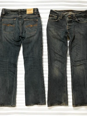 Nudie Jeans Bootcut Ola vintage - Ett par riktigt snygga Nudie jeans i modellen bootcut Ola som slutade tillverkas år 2012! W31 L32. Riktigt bra skick förutom att lappen är urtvättad som man ser på bilden och att det är lite heeldrag men enligt mig gör det bara jeansen snyggare🙌  Längd, 100,5 cm Innermidja, 84 cm Midja rakt över, 40,5 cm Benöppning, 41 cm Benöppning rakt över, 21,5  Måtten kan variera någon cm eftersom jag inte är något proffs på att mäta, Skriv vid frågor🫵