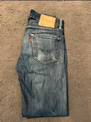Levi’s jeans - Säljer ett par feta levi’s jeans i blå denim med snygg tvätt. Jeansen har fem fickor, läderpatch bak i midjan och den ikoniska röda Levi's-lappen på bakfickan. Perfekta för en avslappnad och trendig stil.