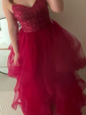Röd glittrig balklänning med volanger - Jättefin röd balklänning med volanger och glitter topp från Zapaka, endast provad men aldrig använd då den var för liten i ryggen, storlek S men passar mer för folk med storlek XS. Lapp finns kvar på klänningen
