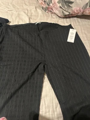 Svarta structure pants från Nelly - Säljer ett par svarta linnebyxor från Nelly med diskret rutmönster i tyget. Byxorna har rak passform och resår i midjan för extra komfort. Perfekta för en avslappnad och stilren look. Tyvärr var de för stora på mig men har aldrig haft på de ute bara testat!