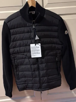 Moncler Cardigan Svart - Svart cardiganjacka från Moncler. Padded zip up med ull. Använd par gånger men börjar bli liten och vill ha något nytt. Storlek M men liten i storlek så passar S. Vid fler frågor osv besvaras i DM🔥Priset går säkert att diskuteras bara vid snabb affär!!
