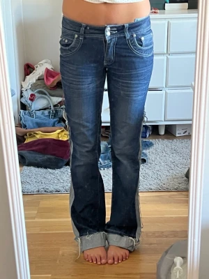 Mörkblå bootcut jeans med kontrastdetaljer -  ett par mörkblå bootcut jeans. Har ett hål vid benet 