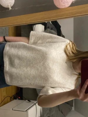 Ljusgrå stickad t-shirt - Säljer en ljusgrå stickad t-shirt med korta ärmar och rund hals. Tröjan har en avslappnad passform och är gjord i ett mjukt, tunt stickat material. Perfekt att styla med jeans eller kjol för en enkel och snygg look. Sticks ej