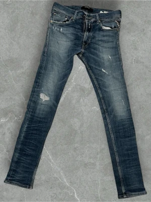 Replay jeans - Säljer ett par blå skinny jeans med slitningar och distressed detaljer. Jeansen har fem fickor, låg midja och klassisk dragkedja med knapp. Perfekta för en avslappnad streetstyle-look.