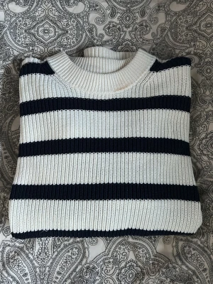 Randig stickad tröja från Bik Bok - Säljer en snygg stickad tröja från Bik Bok i vitt med mörkblå ränder. Finns en liten fläck i urringningen, annars nästan som ny. Använd max 5 gånger.