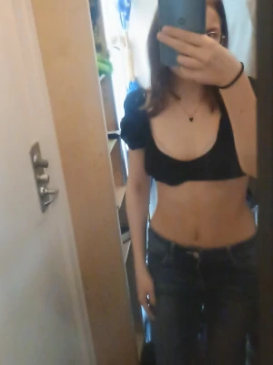 Svart croppad topp med puffärm - Snygg svart croppad topp med puffärmar och öppen rygg. Toppen har snörning i ryggen för justerbar passform och är perfekt för dig som gillar trendiga detaljer. Passar till jeans eller kjol för en cool look.