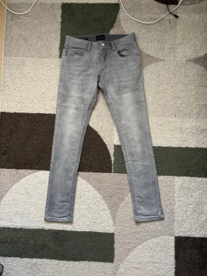 Grå slim fit jeans - Snygga grå jeans i slim fit-modell med klassisk femficksdesign. Jeansen har en diskret tvättad look och raka ben. Perfekta till vardagsstilen och lätta att matcha med olika outfits. Använda ungefär 2 gånger