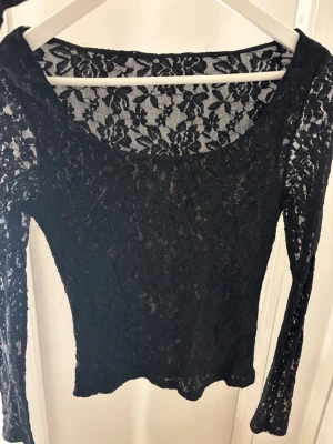 Svart spetströja med lång ärm - Snygg svart spetströja som man kan ha åt båda hållen antingen urringad eller heltäckande med spets. Den är från Nelly men klippt bort lappen. 