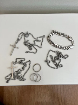 Smyckeset i silverfärgad metall - Säljer ett set med smycken i silverfärgad metall som inkluderar två halsband med korshängen, ett kraftigt armband med breda länkar samt 3 ringar, varav en har tvinnad design. 29kr per smycke (29 för alla 3 ringar), 89 för hela smyckesetet. Halsbanden är alla 55cm långa och armbandet 21cm Tveka inte på att höra av dig ifall du har några frågor!✨
