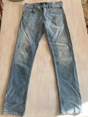 Ljusblå jeans från Replay - Säljer ett par ljusblå jeans från Replay med klassisk femficksmodell och smal passform. Jeansen har snygga slitningar och Replay-logga på myntfickan. Tillverkade i mjuk denim som är sköna att bära hela dagen. Använda endast någon gång.