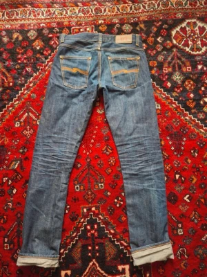 Nudie grim Tim selvage - Säljer ett par feta nudie grim Tim. De är ett par selvage jeans som blir snyggare ju mer de används. Storlek 30:34. Mått: midja 41,5 cm. Längd: 106 cm. Benöppning 18 cm. Hör av er om ni har frågor!