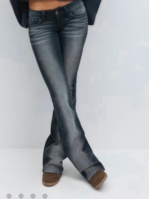 Blå bootcut jeans med nitar - Säljer ett par blå bootcut jeans med coola nitar längs sidorna. Jeansen har låg midja, klassiska fem fickor och snygg tvättad look. Perfekta för dig som vill ha en trendig och unik stil. Materialet är stretchigt denim för skön passform. Omsydda så passar till 160-165!!!!