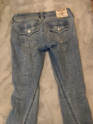 Ljusblå bootcut jeans från true religion  - Jag säljer ett par ljusblå true religion i Stl 25, nästan helt oanvända så nästan i nyskick. Säljer pågrund av att de inte passar mig☺️Orginal pris 1200, mitt pris 820💕