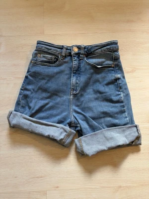 Blå denim shorts med uppvik - Snygga blå denim shorts med hög midja och uppvikta ben. Vikningen är inte fastsydd så man kan välja ”höjd” själv.