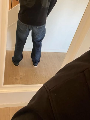Blå Levis bootcut jeans - Säljer ett par klassiska blå Levis  jeans med loose bootcut passform och lätt tvättad look. Jeansen har fem fickor och normal midja. Perfekta för dig som gillar en avslappnad stil. Materialet är denim och färgen är mörkblå med subtila slitningar. Passar någon som bär 33/32