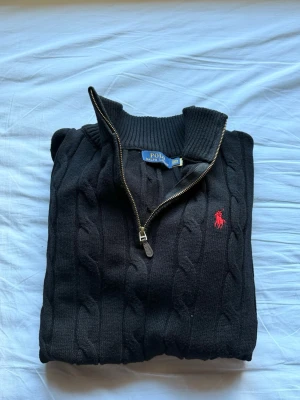 Svart kabelstickad tröja Polo Ralph Lauren - En absolut vacker stickad tröja från ralph lauren. Materialet skulle jag personligen säga är en av dem bästa jag har sätt. Varm och stylig. Tröjan är helt ny och skickad med taggar 
