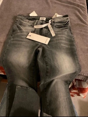 Grå skinny jeans från Vero Moda - Snygga grå skinny jeans från Vero Moda med coola slitningar och tvättad look. Jeansen har klassisk femficksmodell, hällor för bälte och normal midja. Perfekta för dig som gillar en tajt passform och trendig stil.