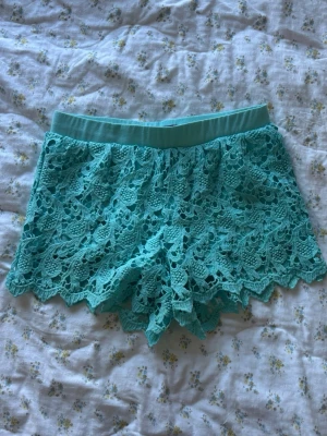 Turkosa spets-shorts från Shinestar - Snygga turkosa shorts från Shinestar med dekorativ spets och elastisk midja. 
