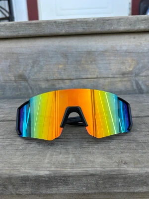 Orange Sportsolglasögon med svart ram - Sportsolglasögon med svart ram och glas som skiftar mellan orange grön och blå , One size storlek för vuxna. Unisex. Nya.  Skickar gärna i bundle.     #sportglasses ##løbebriller #mårdis #polers Valborg #sportsolglasögon #brillor #löparbrillor #löparglasögon #cykelbriller #pink #frame #white #streetwear #sverige #pit #bliz #black #tripleblack #aktivitet #uteaktivitet 