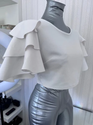 Vit crop sommar topp, Strl M - Jättefin topp med volangärmar, i mycket bra skick! Köpt från ett märke kallat för Prague  Storlek M