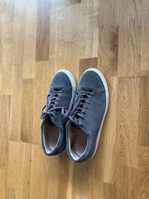Myrqvist sneakers - Säljer ett par stilrena gråa sneakers i mocka med klassisk vit sula och snörning. Skorna har låg profil och är perfekta för dig som gillar en enkel och clean look. Passar till jeans och t-shirt eller hoodie.