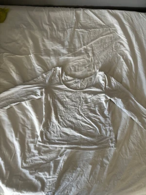 Vit långärmad topp från Lindex - En basic vit långärmad topp från Lindex med rundad halsringning. Tillverkad i mjukt och stretchigt material som känns skönt mot huden. Perfekt att styla lager på lager eller bära som den är.