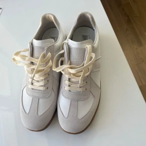 Vita sneakers från Maison Margiela - Hej säljer nu ett par snygga masion margelia skor i storlek 46. Skorna är hely nya. Priset är ej hugget i sten och det är bara att skriva om frågor!