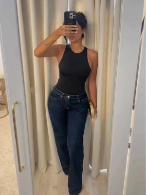 Svart body från Zara - Snygg svart body från Zara med hög halsringning och ärmlös design. Tillverkad i stretchigt material som sitter tight och bekvämt mot kroppen. Perfekt att styla med jeans eller kjol för en clean look💕