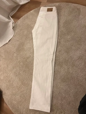 Vita raka jeans från 157 - Säljer ett par vita jeans från 157 med rak passform och vanliga bakfickor. Jeansen har normal midja och är tillverkade i ett kraftigare denimtyg. Perfekta för dig som vill ha en clean och stilren look. Modellen är ICON