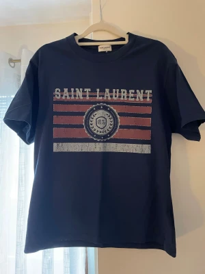 Saint Laurent T-shirt - Säljer denna feta yls tröjan. Köpt på plick förra sommaren men aldrig fått någon användning av den. Hör av dig vid minsta fundering😄