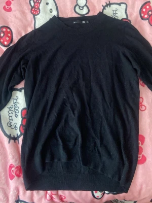 Svart basic stickad tröja från lager - En enkel och stilren svart stickad tröja från Lager 157. Tröjan har rund halsringning, långa ärmar och ribbade muddar vid ärmslut och nederkant. Perfekt basplagg i garderoben och lätt att matcha med olika stilar.