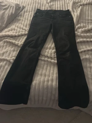 Svarta bootcut jeans från Lee - Säljer ett par svarta bootcut jeans från Lee med klassisk femficksmodell och dragkedja. Jeansen har hög midja och utsvängda ben, perfekta för en trendig och avslappnad look. Tillverkade i mjukt denimtyg som sitter snyggt och bekvämt. Slitna på ändarna. W28 och L31