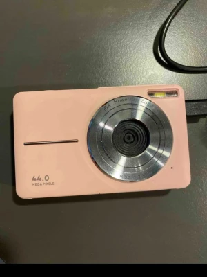 Rosa digitalkamera 44MP 16x zoom - Snygg rosa digitalkamera med 44 megapixlar och 16x optisk zoom. Kameran har en kompakt rektangulär form, inbyggd blixt och en stor rund lins i metall. Perfekt för dig som vill ta skarpa bilder med stil. USB-port för laddning och överföring.