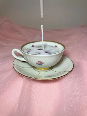 Doftljus i en vaniljdoft u en tekopp med fat med blommig design  - Det här ljuset är gjort av återanvändbara material. Tekoppen är köpt secondhand och stearinet är från kyrkor som tänkte slänga det. Det här ljuset har en svag doft utav vanilj, så känsliga även kan använda det. Det här ljuset har även torkade blommor på som dekoration. 