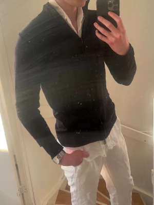 Mörkblå ziptröja från Oscar Jacobsson - Snygg mörkblå ziptröja med hög ribbad krage och hel dragkedja framtill. Tröjan har en smal passform och är tillverkad i ett tunt, mjukt material som passar perfekt till lager-på-lager. Enkel och stilren design utan synliga loggor. Den har ett hål vid framsidan men är annars i ett bra skick.