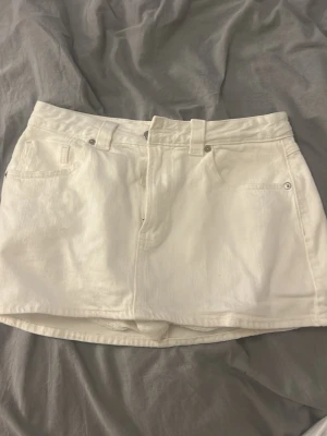 Vit jeanskjol från stradivarius - Snygg vit kort jeanskjol med låg midja. De finns inbyggda shorts, och dom är i storlek 38. Säljer för att dom är för stora, aldrig andvända.