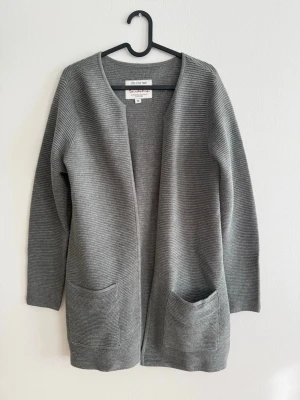 Bondelid kofta - Strl M - Snygg och tidlös kofta från Bondelid i en klassisk grå färg. Perfekt som lager över t-shirt, skjorta eller klänning året runt. Väldigt skön och lätt att matcha.  • Storlek: M • Längd: ca 78 cm • Material: 50% bomull / 50% akryl • Märke: Bondelid • Skick: Väldigt fint skick  Kvalitetsplagg från ett välkänt svenskt märke. Koftan har två framfickor och en avslappnad passform som passar till både vardag och jobb.