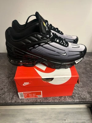Nike Air Max Plus Tn svart/grå - Nike Air Max Plus Tn sneakers i svart och grått med futuristisk design och tydliga linjer på ovandelen. Skorna har synlig Air Max-dämpning i sulan, mesh och syntetmaterial samt klassisk Tn-logga på plösen. Sitter på en robust svart sula och har svarta snören.