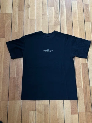 Svart Maison Margiela t-shirt - Svart t-shirt från Maison Margiela med diskret vit logotyp på bröstet. Klassisk rund halsringning och normal passform. Tillverkad i mjuk bomull som känns skön mot huden. Perfekt för dig som gillar minimalistisk och stilren design.