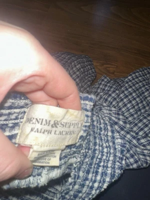 Blårutig blus från Denim & Supply - Söt blårutig blus från Denim & Supply Ralph Lauren. Tillverkad i 100% bomull med smockad resår vid halsringningen och ärmsluten. Blusen har korta ärmar och ett avslappnat, luftigt snitt. Perfekt till jeans eller kjol för en casual look.( köpte den för 1000kr