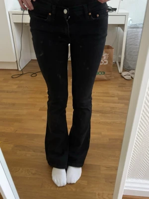 Svarta bootcut jeans med hög midja - Säljer ett par svarta bootcut jeans med låg midja och klassiska fem fickor. Jeansen har en snygg passform som sitter tight över låren och släpper ut vid vaden. Perfekta till sneakers eller boots och passar till många olika stilar. Innerbens längd: 76cm och midjemått 32, de är stretchiga, de är i storlek 34