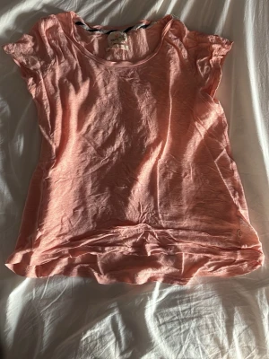 Ljusrosa t-shirt med rund hals - En enkel och snygg ljusrosa t-shirt med rund halsringning och korta ärmar. Tillverkad i mjukt bomullsmaterial som känns skönt mot huden. 