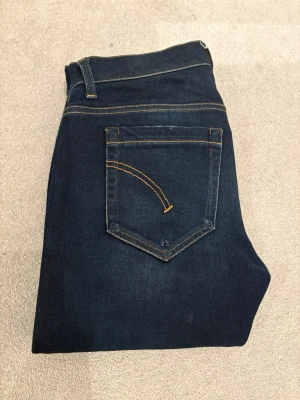 Mörkblå Dondup jeans  - Snygga mörkblå skinny fit jeans från Dondup med klassiska kontrastsömmar och femficksmodell. Modell George. Jeansen har en diskret logga på bakfickan och är tillverkade i stretchig denim för extra komfort. Perfekta för dig som gillar en stilren och modern look.