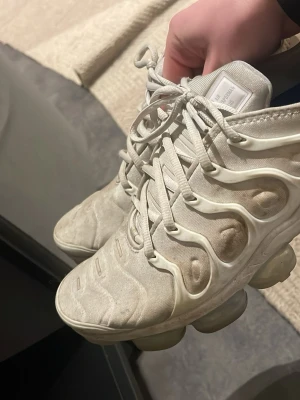 Vita Nike Air Vapormax Plus sneakers - Nike Air Vapormax Plus sneakers i vitt med futuristisk design och synliga luftbubblor i sulan. Ovandelen är i textil med plastdetaljer och snörning. Perfekta för dig som gillar streetwear och vill ha en unik look. Har inte kvitto kvar tyvärr men kosta 2800 nya köpta från Zalando 