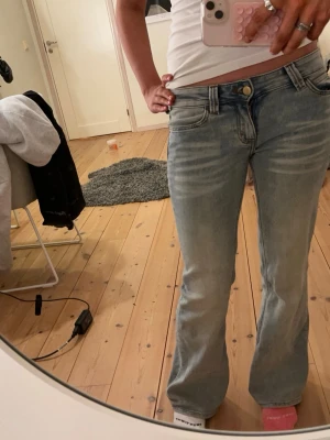 Ljusblå bootcut jeans från Cheap Monday - Säljer ett par ljusblå bootcut jeans från Cheap Monday med klassisk femficksdesign och låg midja. Jeansen har en snygg tvättad look och grönt Cheap Monday-märke på bakfickan. Perfekta för dig som gillar en avslappnad och trendig stil.